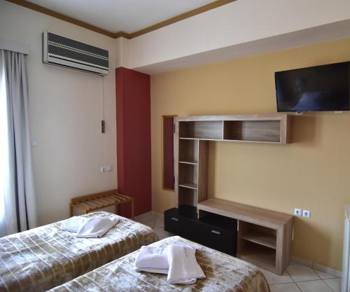 a hotel room with two beds and a flat screen tv at Iridanos in Antikyra