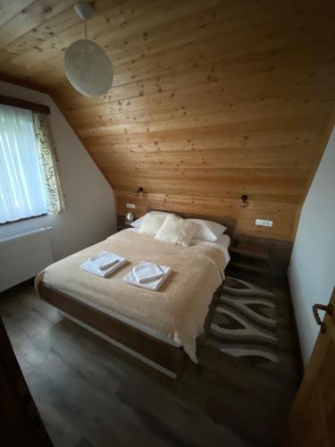 a large bed in a room with a wooden ceiling at House Flora in Rastovača