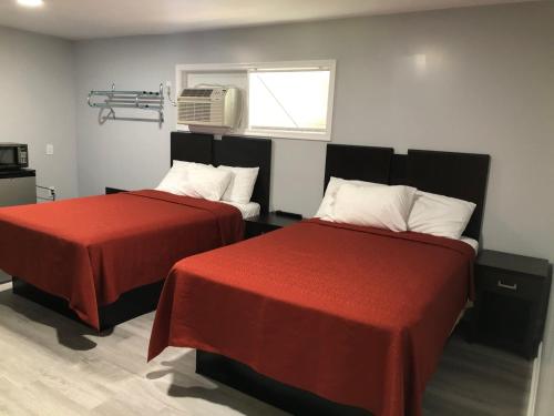 a room with two beds with red sheets and a window at Bay Inn Hotel in North Camellia Acres