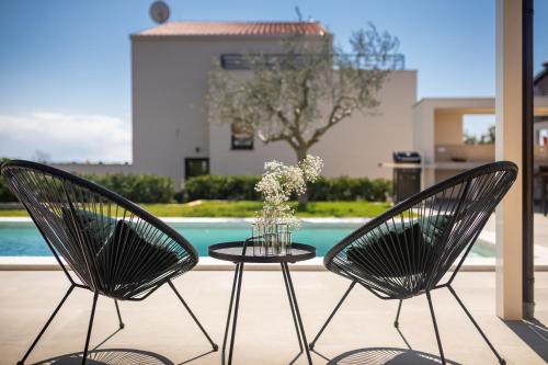 two chairs and a table with a vase of flowers at Belvedere Holidays Villas in Novigrad Istria