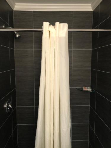 La salle de bains est pourvue d'une douche avec un rideau de douche blanc. dans l'établissement Bay Inn Hotel, à North Camellia Acres