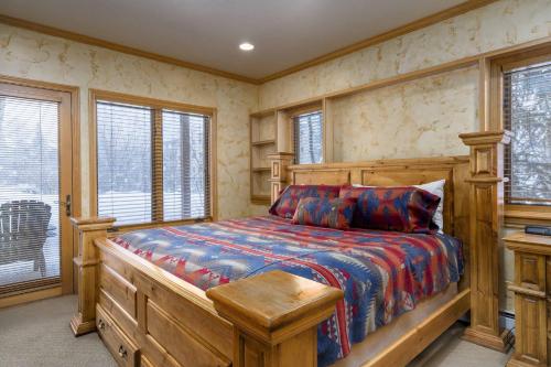 a bedroom with a wooden bed in a room with windows at Evergreens 04 in Steamboat Springs