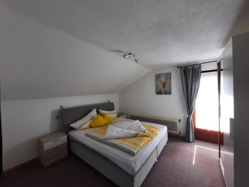 Un dormitorio con una cama con almohadas amarillas y una ventana en Haus Waldfrieden, en Sautens