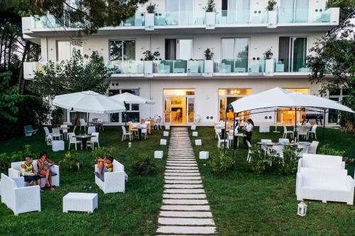 a garden with white chairs and tables in front of a building at Hotel Artemide Mare in Paestum
