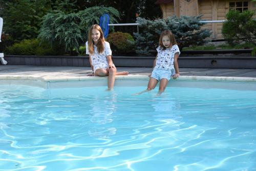 deux petites filles assises au bord d'une piscine dans l'établissement Les jardins d'armance, à Le Valdahon