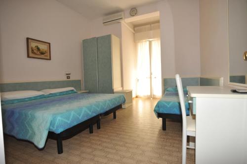 une chambre d'hôtel avec deux lits et une cuisine dans l'établissement Hotel Metron, à Cesenatico