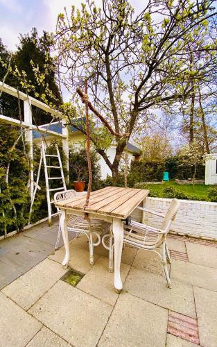a wooden picnic table and a bench next to a tree at De Tuinkamer-----Privé diner op de kamer mogelijk!!! in Hoogeveen