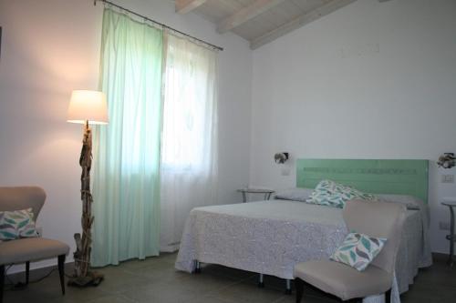 ein Schlafzimmer mit einem Bett, zwei Stühlen und einer Lampe in der Unterkunft Agriturismo podere 678 in Grosseto