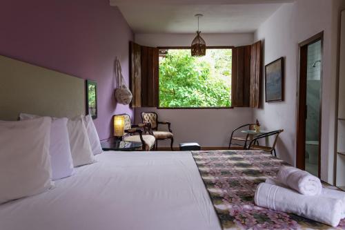 a bedroom with a large white bed with a window at Pousada Arvoredo in Pirenópolis