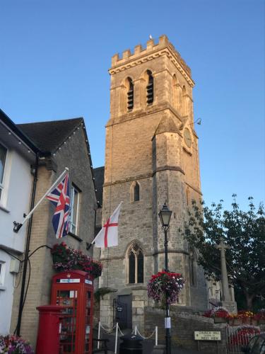 an old church with a tower and flags in front of it at Minton House in Colyton