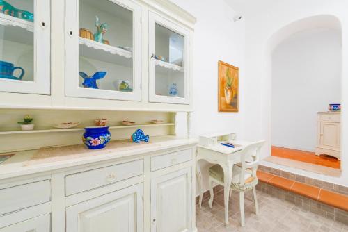 uma cozinha com armários brancos e uma mesa em Casa Pietro em Positano