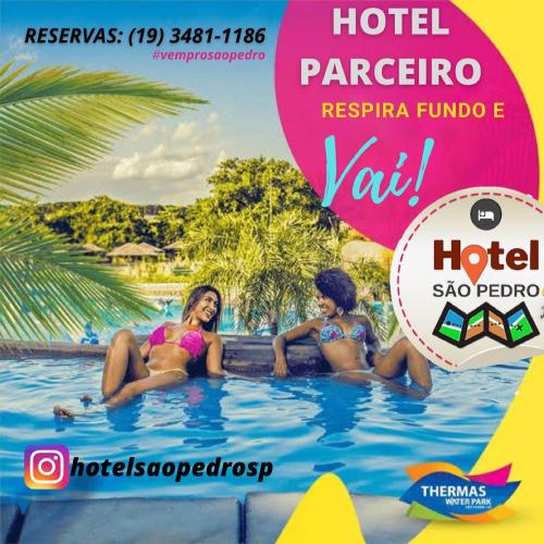 two girls sitting in a swimming pool at a hotel at Hotel São Pedro in São Pedro