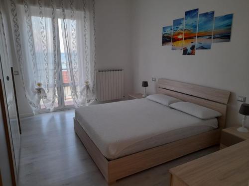 法爾科納拉馬里蒂馬的住宿－Appartamento Fronte Mare，卧室配有一张床,墙上挂有绘画作品