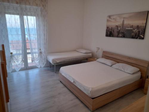 - une chambre avec 2 lits et une grande fenêtre dans l'établissement Appartamento Fronte Mare, à Falconara Marittima
