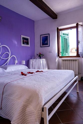 a bedroom with a white bed and a purple wall at Solemagia in Vernazza