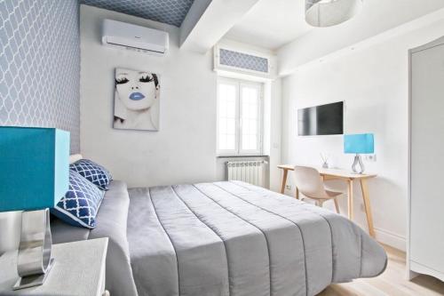 a white bedroom with a large bed and a desk at Hotel La Maison Delle Terme in Tivoli Terme