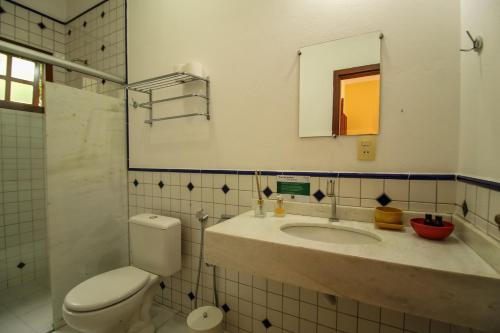 a bathroom with a sink and a toilet and a mirror at Pousada Arvoredo in Pirenópolis