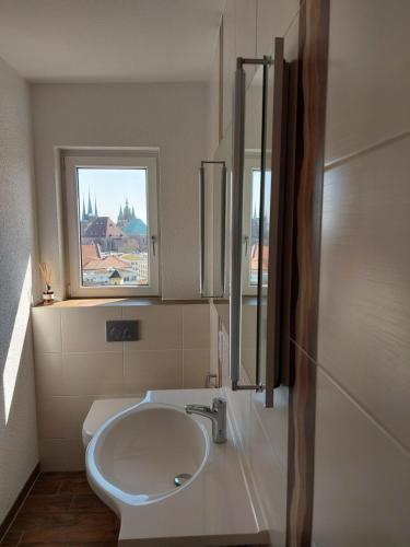 ein weißes Bad mit einem Waschbecken und einem Fenster in der Unterkunft AT THE TOP - Penthouse über den Dächern der Stadt in Erfurt