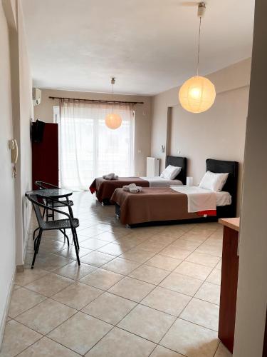 a bedroom with two beds and a table in it at Theros Apartment Preveza in Preveza