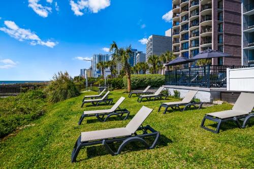 a row of chaise lounges on the grass near a building at The Beverley Beach House in Myrtle Beach