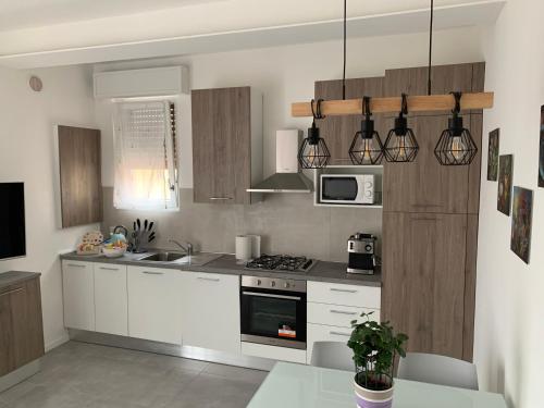 una cucina con armadi bianchi e piano cottura di Comfort Apartment Verona a Verona