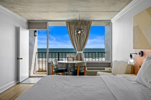 a bedroom with a bed and a table with a view of the ocean at The Beverley Beach House in Myrtle Beach