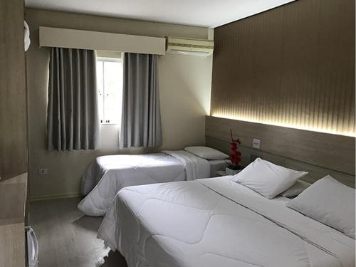a hotel room with two beds and a window at Resort Campo Belo in Álvares Machado