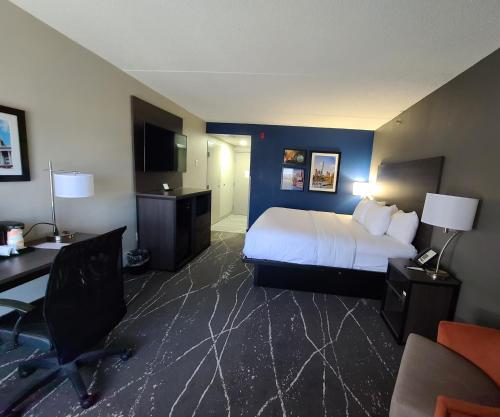 a hotel room with a bed and a desk and chair at Comfort Inn Boston Milford in Milford