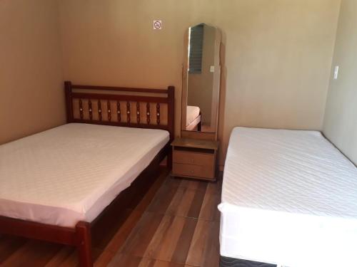 two beds in a small room with a mirror at Rancho Do Claudim in Pirenópolis
