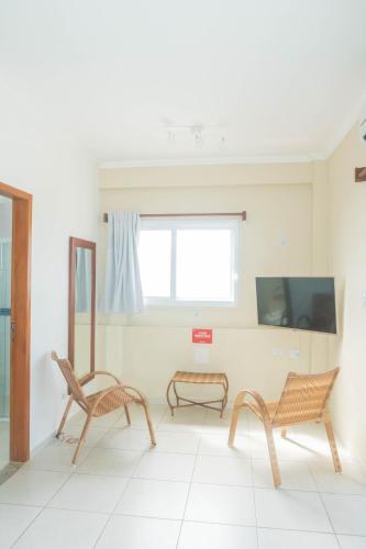 a living room with two chairs and a tv at UPG Hotel in Ubatuba