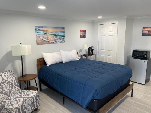 um quarto com uma cama azul e uma cadeira em The Surf Beach Motel em Amelia Island