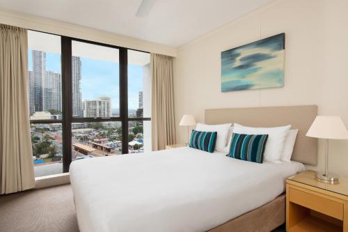 um quarto com uma grande cama branca e uma grande janela em BreakFree Beachpoint em Gold Coast