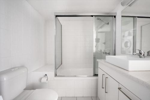 ein weißes Bad mit einer Dusche und einem Waschbecken in der Unterkunft BreakFree Beachpoint in Gold Coast