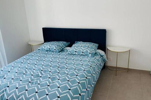 - un lit avec une couette bleue et 2 tables dans l'établissement Wonderful apartment near Monaco and the beach, à Roquebrune-Cap-Martin