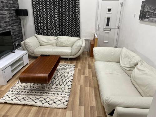 a living room with two white couches and a coffee table at Potters Lodge, Oldham, Manchester by Edl Ventures Ltd in Oldham