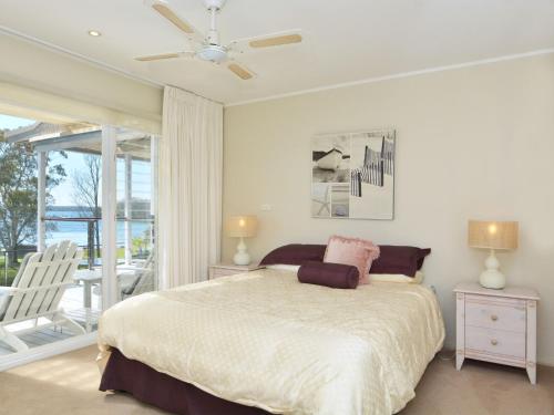 a bedroom with a large bed and a balcony at Lake Macquaries' Edgewater Lakehouse at Morisset Memories in Morisset East
