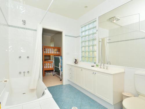 a white bathroom with a tub and a sink and a toilet at Lake Macquaries' Edgewater Escape at Morisset Memories in Morisset