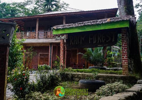 een stenen huis met een bord ervoor bij Rain Forest Guest House in Bukit Lawang