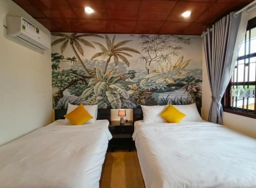 two beds in a room with a painting on the wall at La'ANh Boutique Stay in Can Tho