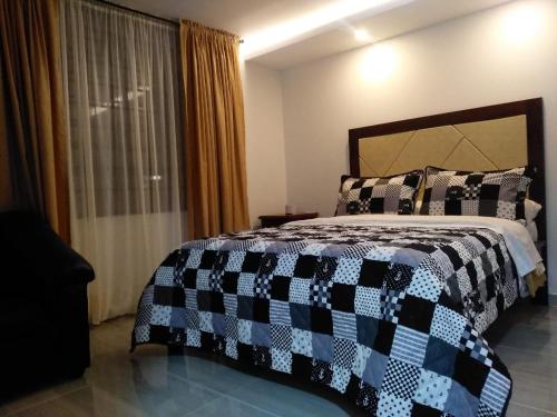 ein Schlafzimmer mit einem Bett mit einer schwarzen und weißen Decke in der Unterkunft HOTEL UNICO in Pasto