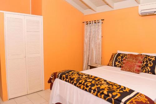 um quarto com paredes cor de laranja, uma cama e uma janela em Perfect vacation villa em Montego Bay