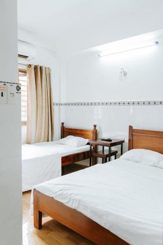 a white room with two beds and a window at 5H homestay in Hue