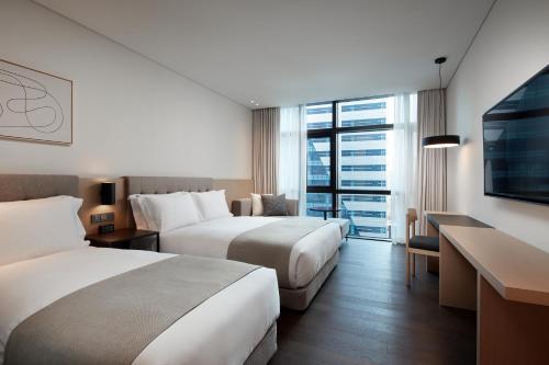 a hotel room with two beds and a flat screen tv at Shilla Stay Busan Gimhae Airport - Noksan in Busan