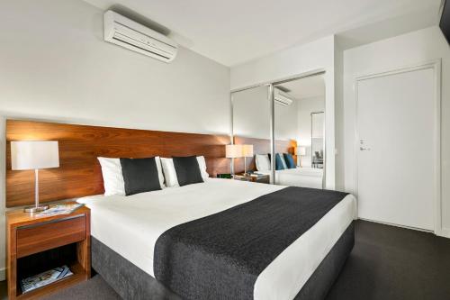 1 dormitorio con 1 cama grande y espejo en Quest Dubbo, en Dubbo
