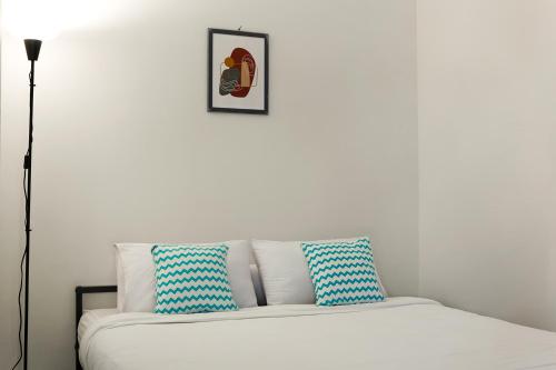 a white couch with blue and white pillows on it at Social Hub by TwoSpaces in Jakarta