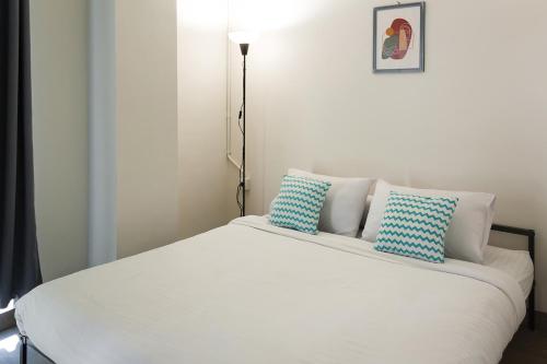 a white bed with two blue pillows on it at Social Hub by TwoSpaces in Jakarta