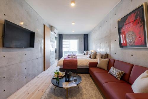 a room with a bed and a couch and a tv at Tamatsukuri Daifuji Kan in Osaka