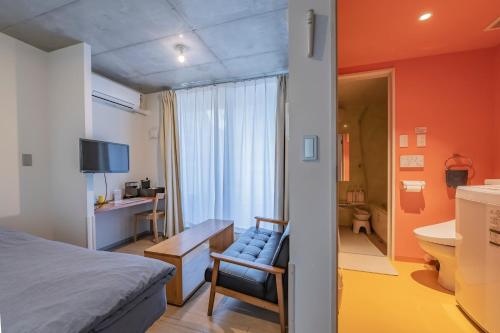 a bedroom with a bed and a chair and a bathroom at bmj Shinjuku Okubo in Tokyo