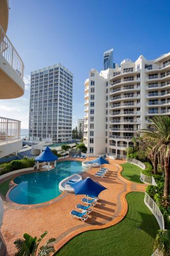 a resort swimming pool with blue umbrellas and chairs at BreakFree Moroccan in Gold Coast
