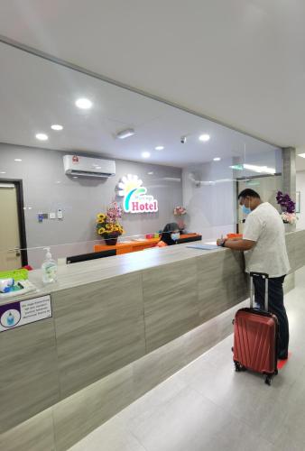 un hombre parado en un mostrador de hotel con una maleta en MORNINGS HOTEL, en Sungai Petani